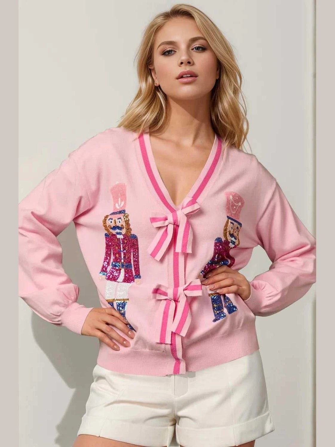 Woman wearing a pink cardigan with character designs on a plain background