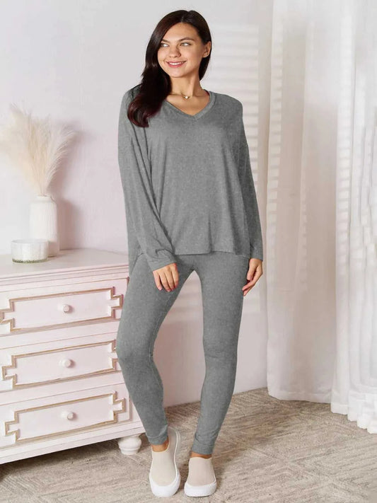 Woman wearing a gray loungewear set in a room with a white dresser.