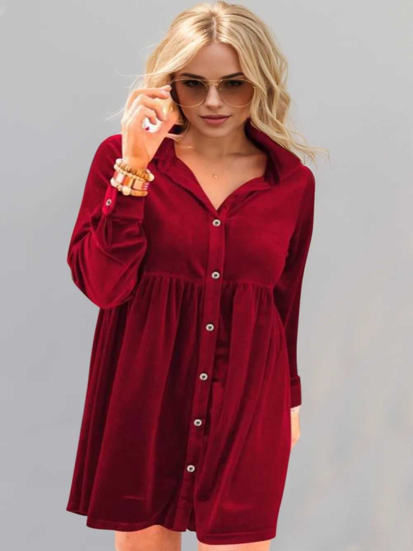 Woman wearing a red dress with long sleeves against a gray background