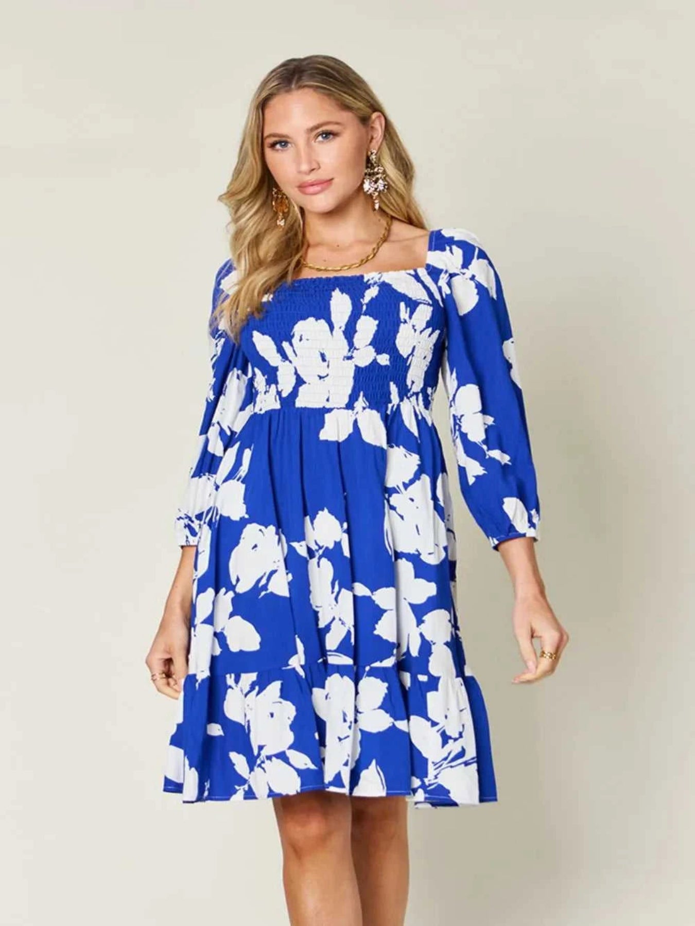 Woman wearing a blue floral dress against a plain background