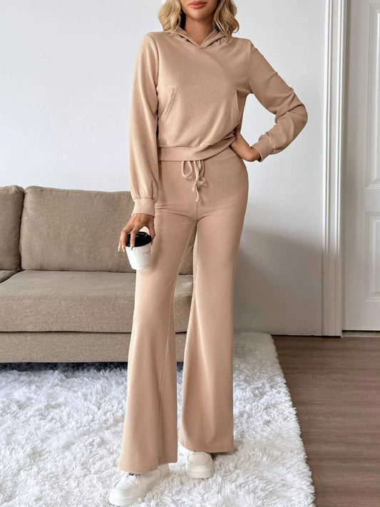 Person wearing a beige tracksuit standing in a living room.